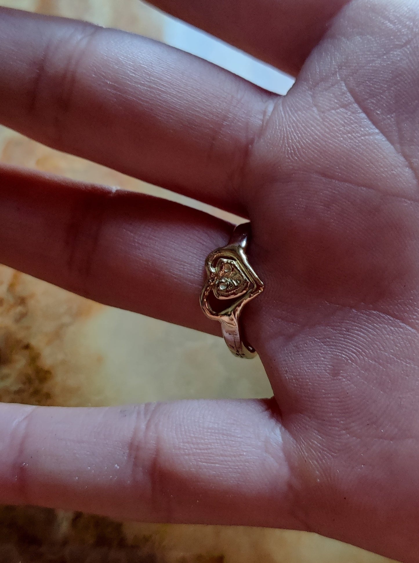 ring in het geel en wit goud. Aan de bovenkant zit er een groen edelsteen hart met pootjes en aan de onderkant van de ring is er een geelgouden oriëntaals geïnspireerd hart. Het groene hart van smaragd is bol.