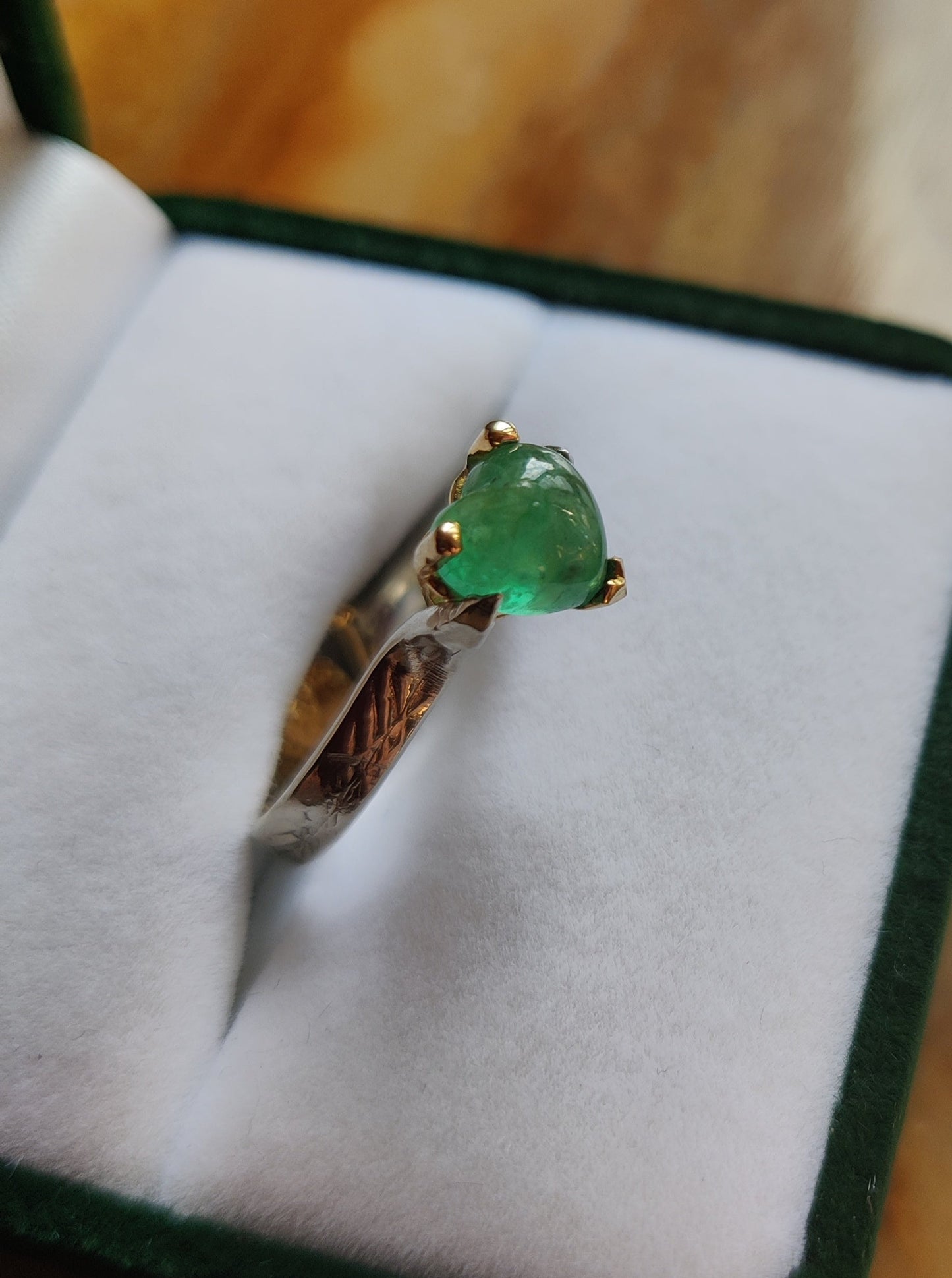 ring in het geel en wit goud. Aan de bovenkant zit er een groen edelsteen hart met pootjes en aan de onderkant van de ring is er een geelgouden oriëntaals geïnspireerd hart. Het groene hart van smaragd is bol.