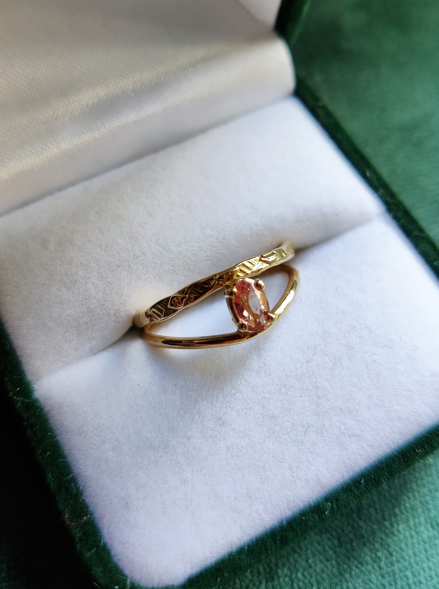 Ring met prachtige roze saffier. De ovale steen heeft de kleur van een perzik en zit met pootjes vast. Het is een fijne ring met dunne bandjes. De bandjes zijn opengewerkt en hebben een blaadjes patroon. De ring is open in het midden en daartussen zit de steen. Saffier is de geboortesteen van september en is erg hard.