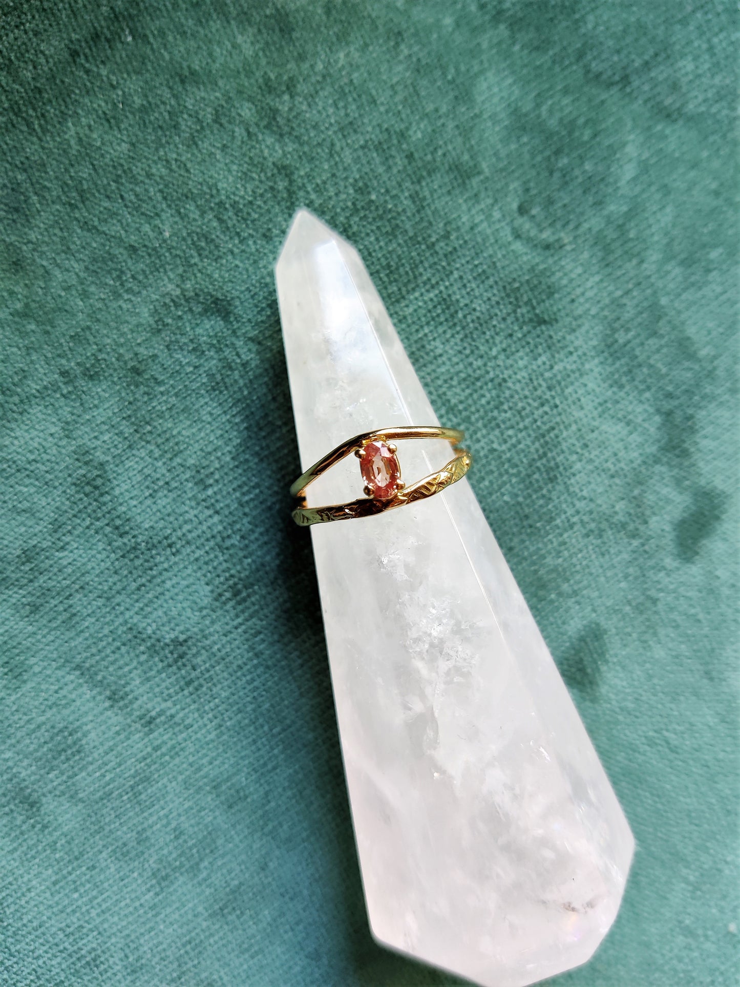 Ring met prachtige roze saffier. De ovale steen heeft de kleur van een perzik en zit met pootjes vast. Het is een fijne ring met dunne bandjes. De bandjes zijn opengewerkt en hebben een blaadjes patroon. De ring is open in het midden en daartussen zit de steen. Saffier is de geboortesteen van september en is erg hard.