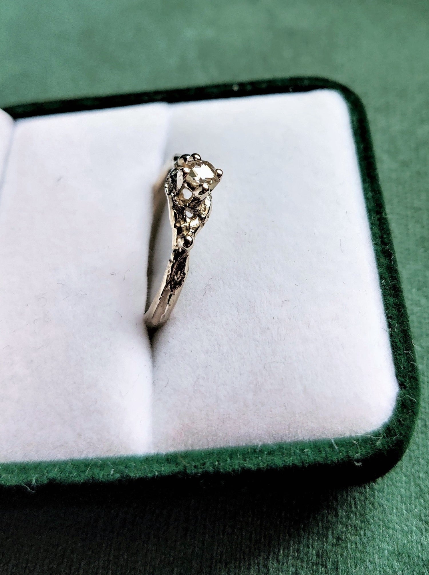 Een verlovingsring met een vintage look and feel in het wit goud. Een solitair met een roosgeslepen diamant dat in een opengewerkt bandje staat.