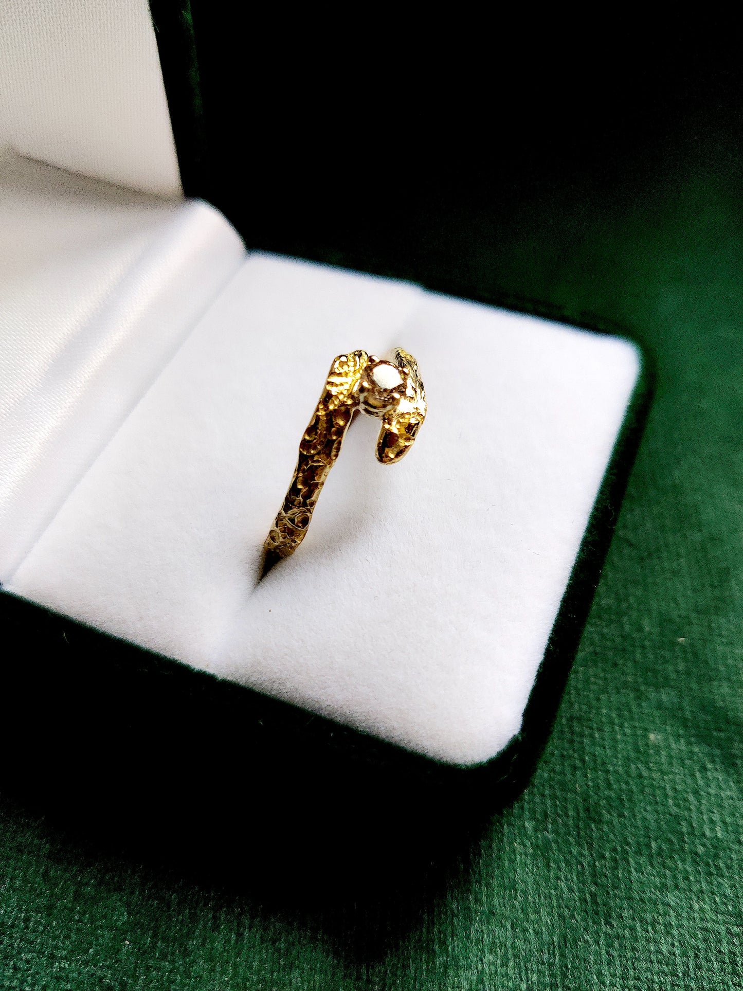 De diamant is gezet in pootjes en staat tussen de open band van de ring. De ring heeft een oriëntaals motief.