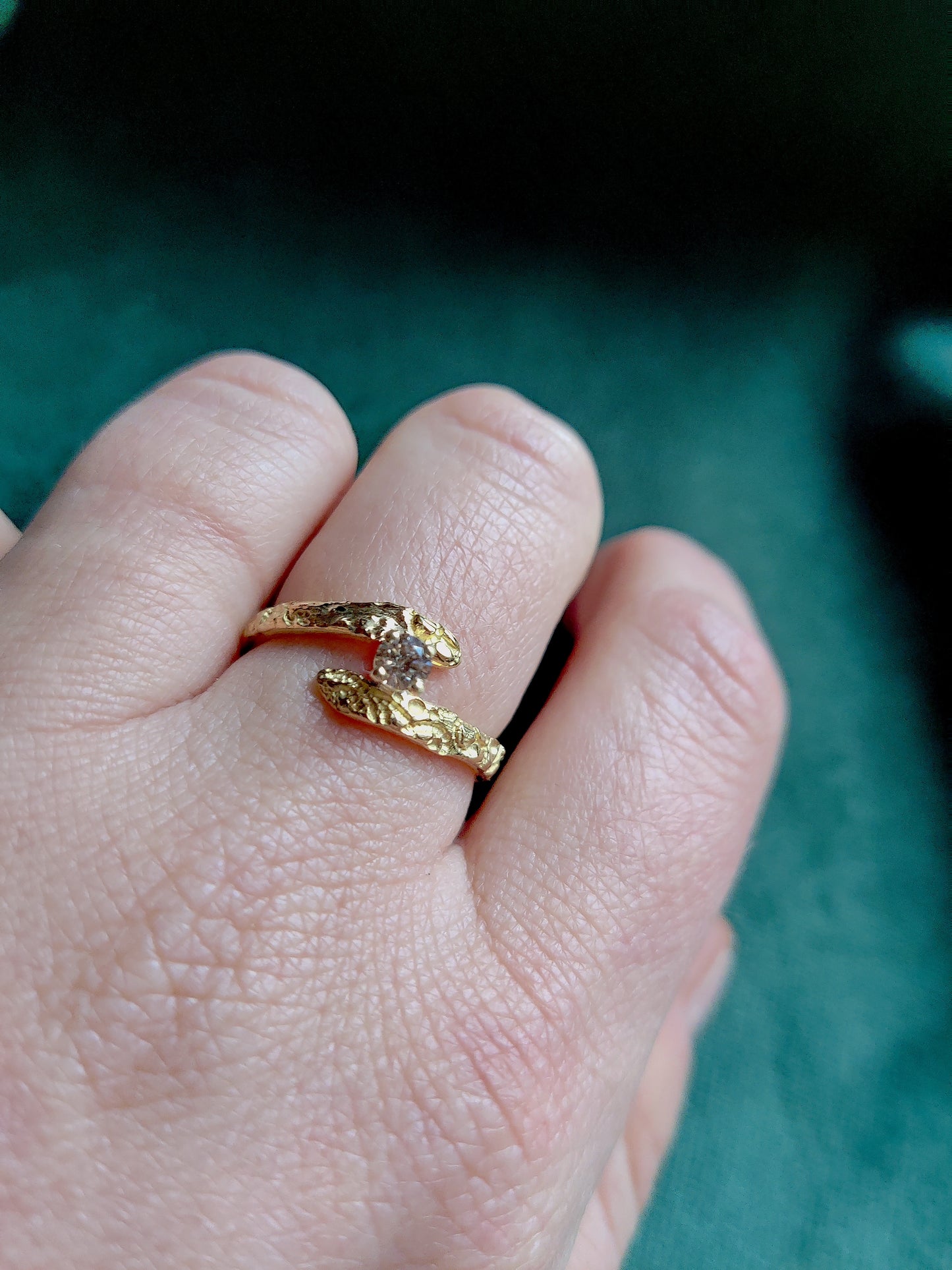 De diamant is gezet in pootjes en staat tussen de open band van de ring. De ring heeft een oriëntaals motief.