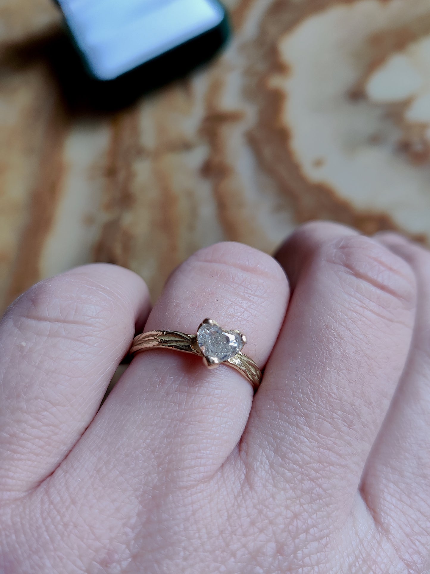 Een verlovingsring met hartvormige diamant gezet in pootjes in een organisch bandje. In het bandje zit precies een bloemenpatroon gegraveerd. Het is een organische band met solitair steen.