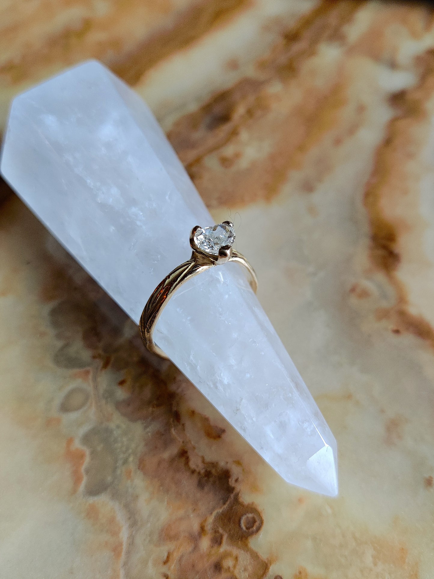 Een verlovingsring met hartvormige diamant gezet in pootjes in een organisch bandje. In het bandje zit precies een bloemenpatroon gegraveerd. Het is een organische band met solitair steen.