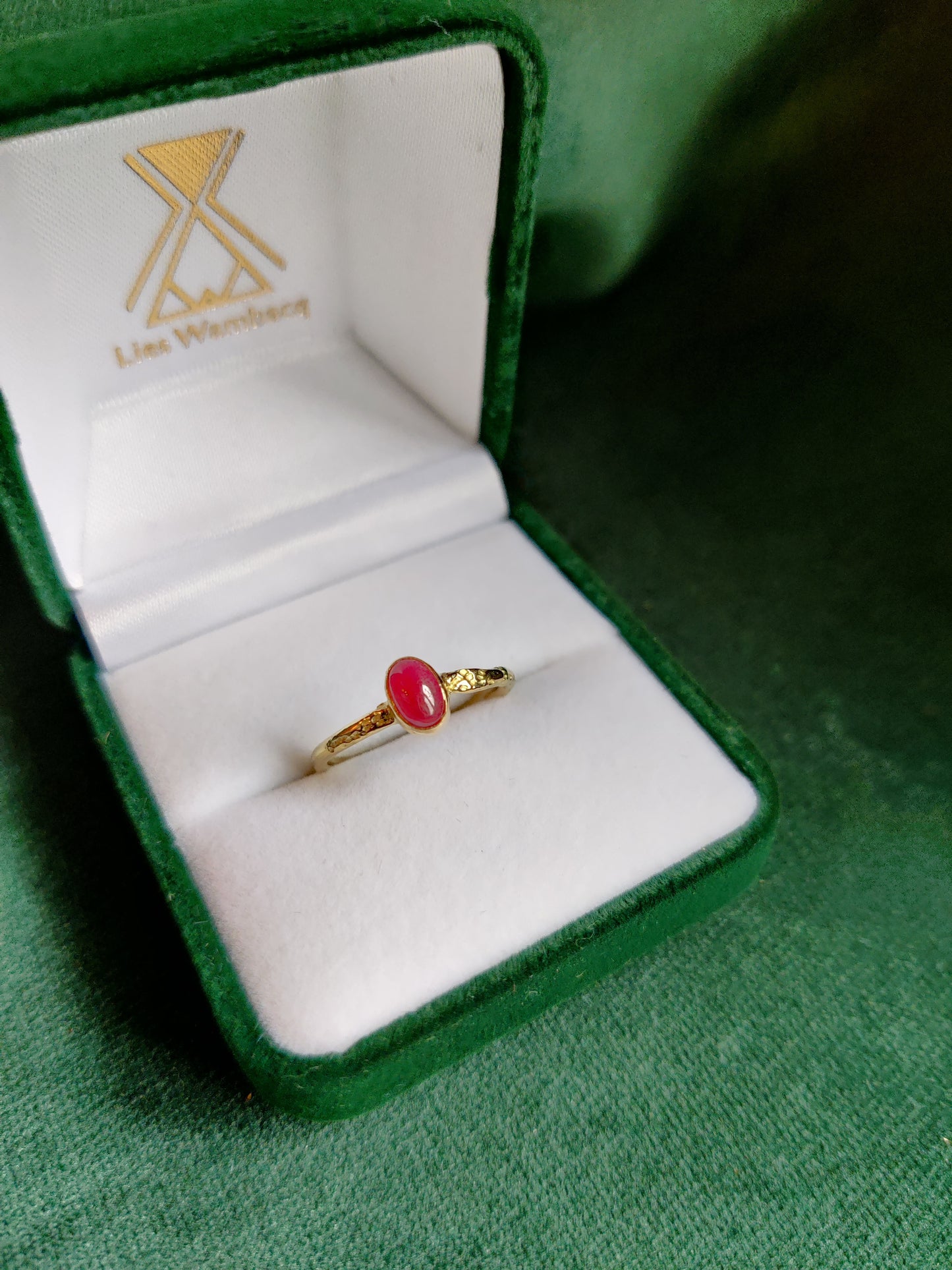 18K geel gouden ring met een matte ovale robijn. De rode edelsteen is in een toe potje gezet op een band met motief. Een romantische stoere en fijne ring.