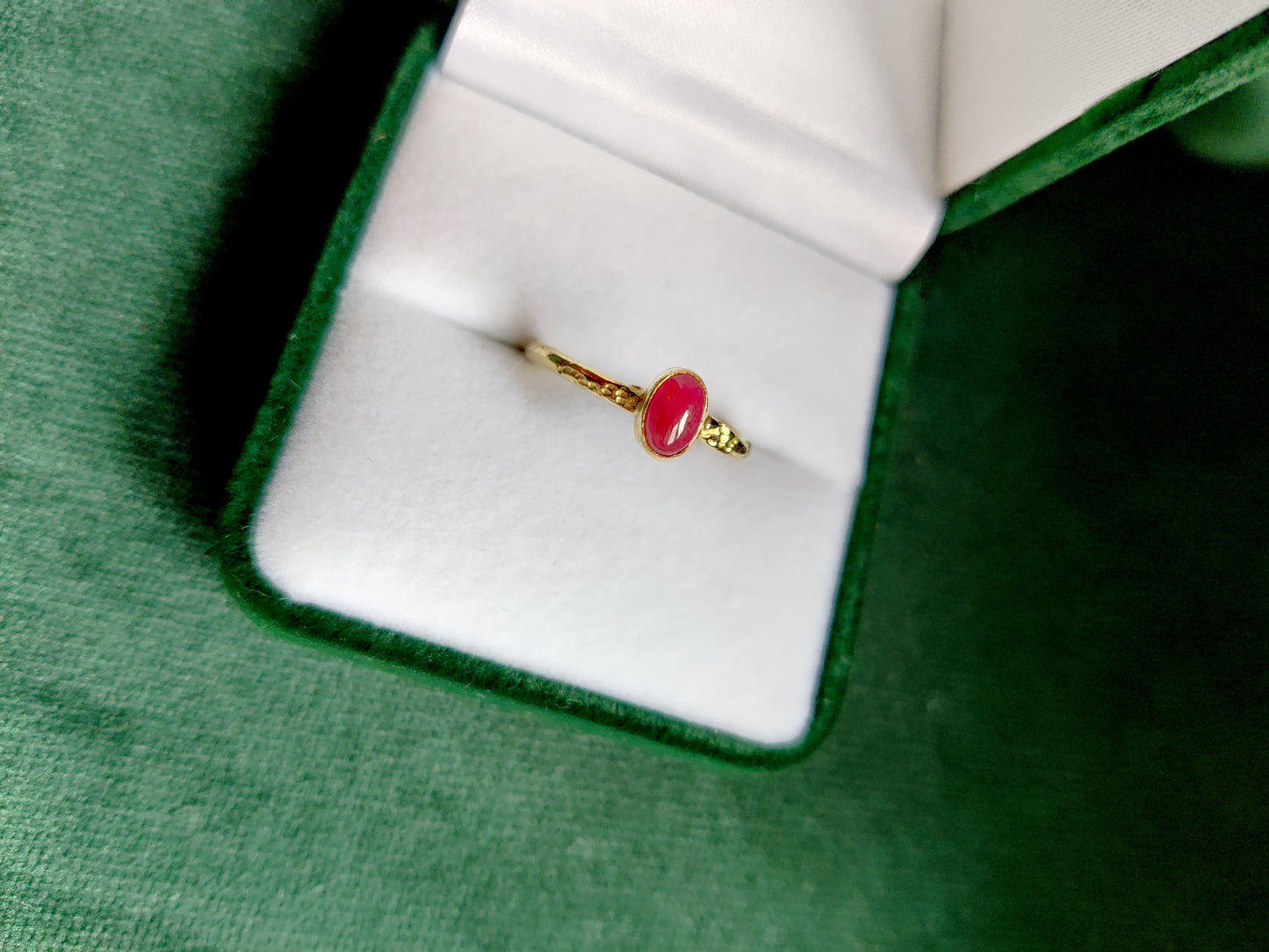 18K geel gouden ring met een matte ovale robijn. De rode edelsteen is in een toe potje gezet op een band met motief. Een romantische stoere en fijne ring.