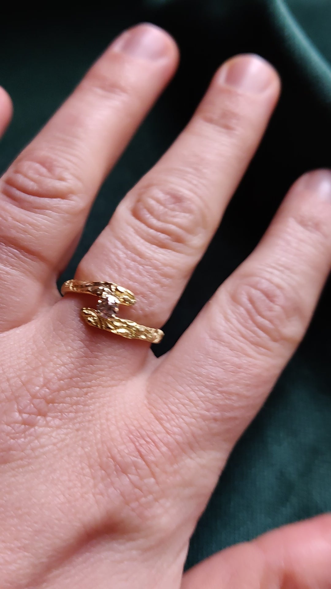 De diamant is gezet in pootjes en staat tussen de open band van de ring. De ring heeft een oriëntaals motief. 