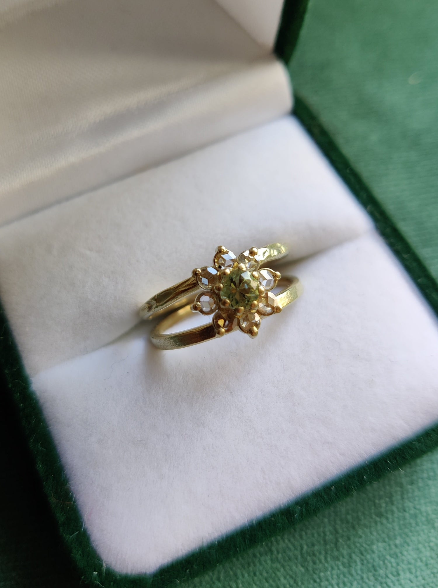 Een unieke originele ring met open bandje. De bandjes hebben een uniek patroon dat lijkt op bloemetjes. In het midden zit een bloemvorm met steentjes. Groene ronde saffier en antiek roos geslepen diamanten.