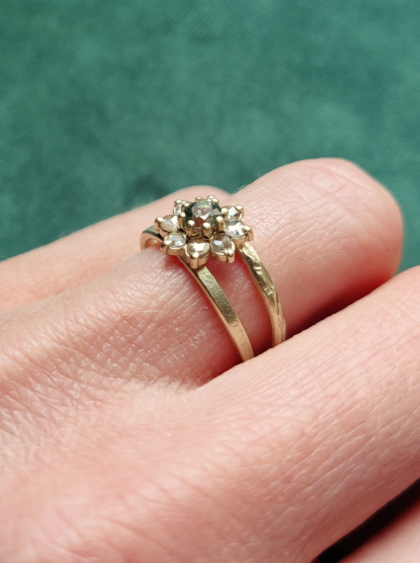 Een unieke originele ring met open bandje. De bandjes hebben een uniek patroon dat lijkt op bloemetjes. In het midden zit een bloemvorm met steentjes. Groene ronde saffier en antiek roos geslepen diamanten.