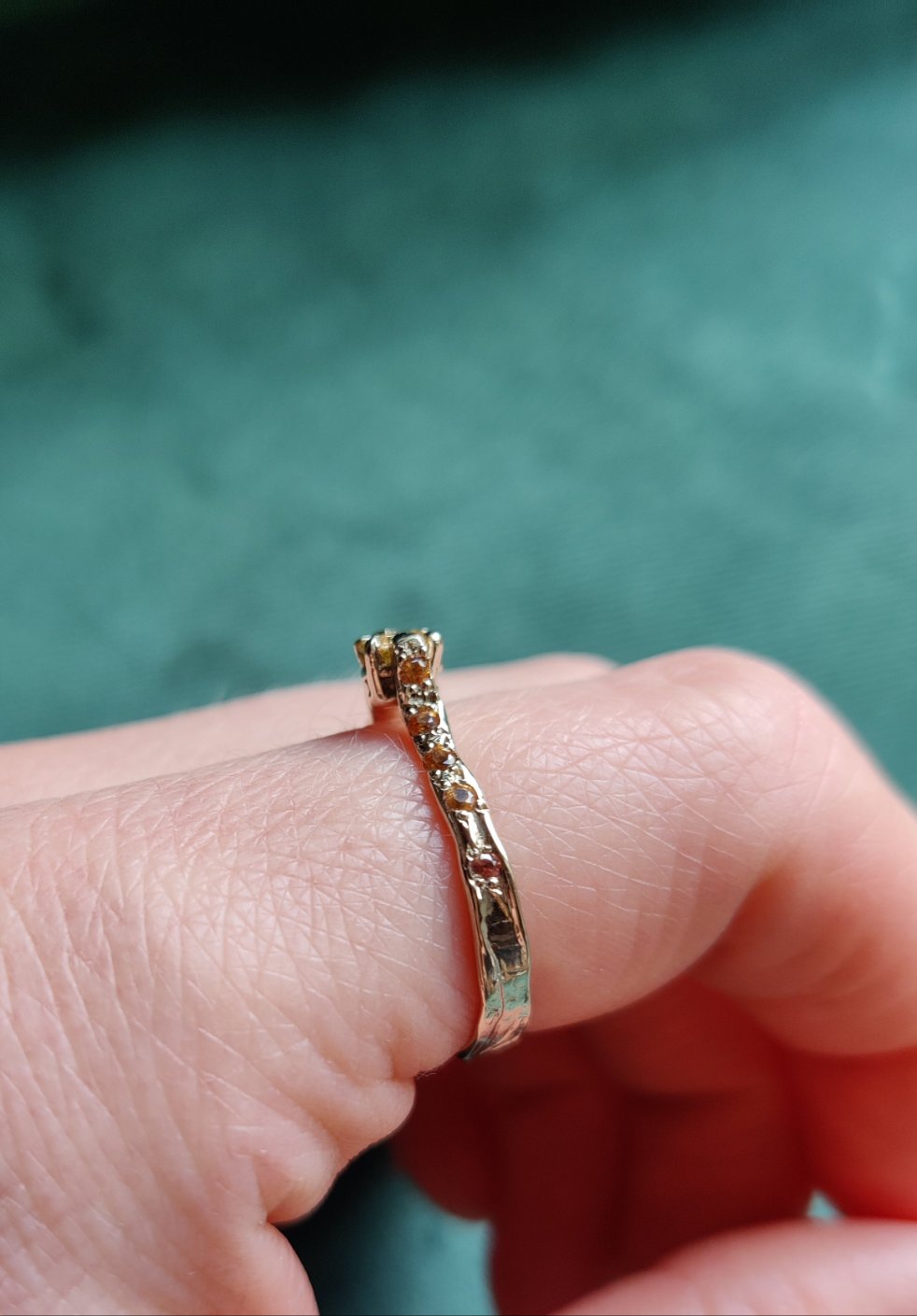 Een verlovingsring waar er maar één van is. Het bandje is wat ruwer, bruter gemaakt. De ring heeft een organisch gevoel en is de combinatie van natuurlijk witgoud en een natuurlijke gekleurde ovalen diamant. Aan de zijkanten zitten oranje saffieren.