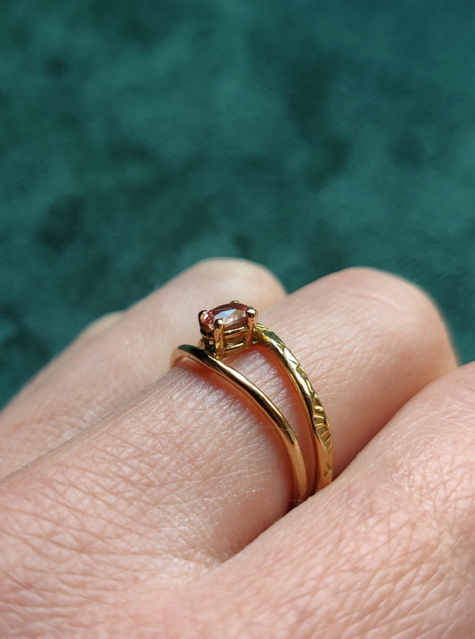 Ring met prachtige roze saffier. De ovale steen heeft de kleur van een perzik en zit met pootjes vast. Het is een fijne ring met dunne bandjes. De bandjes zijn opengewerkt en hebben een blaadjes patroon. De ring is open in het midden en daartussen zit de steen. Saffier is de geboortesteen van september en is erg hard.