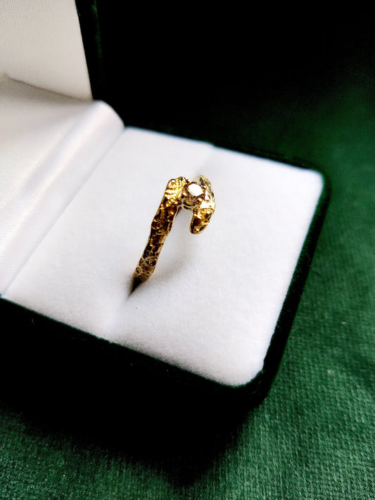 De diamant is gezet in pootjes en staat tussen de open band van de ring. De ring heeft een oriëntaals motief.