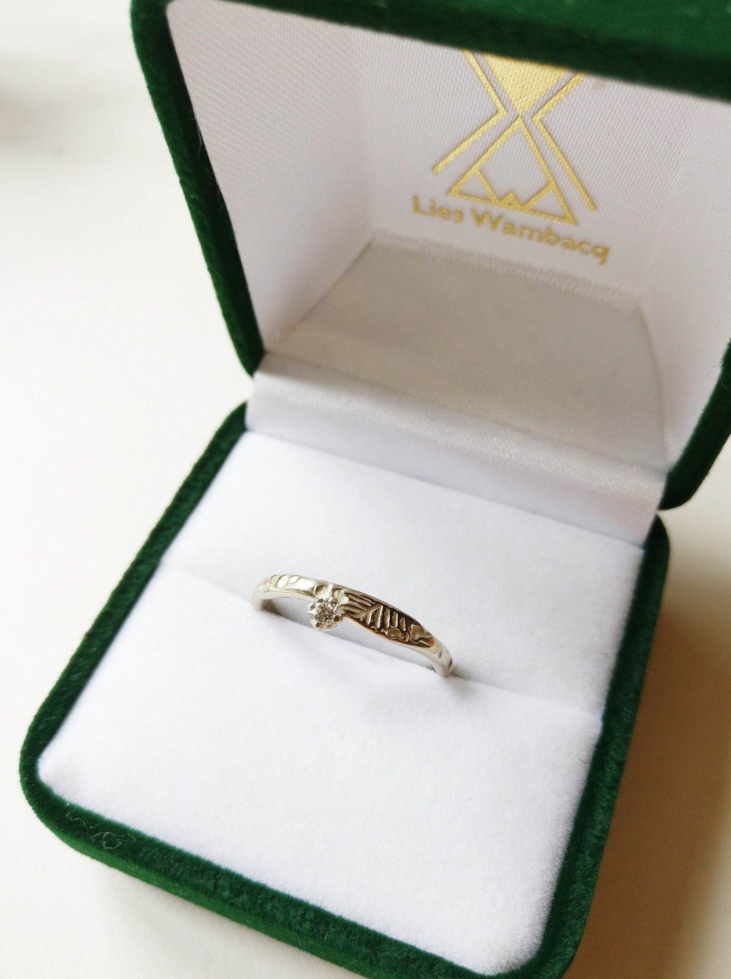 Eva ring 18K palladium wit goud met diamant. De diamant is langs de zijkant van de ring geplaatst. Assymetrisch.